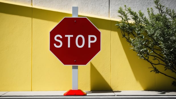 A stop sign is shown against a yellow wall photo