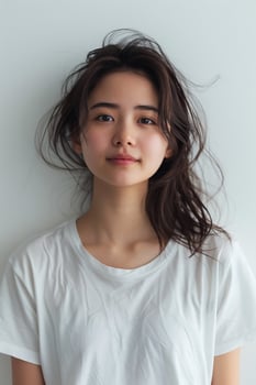 Asian girl with an enchanting smile, dressed in a white t-shirt, photographed against a white backdrop, clear and vivid image photo