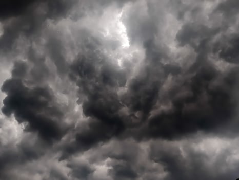 Dark, looming storm clouds dominate the sky, creating a moody, dramatic atmosphere. The overcast sky hints at an impending rainstorm, with thick clouds rolling in and covering the horizon. photo