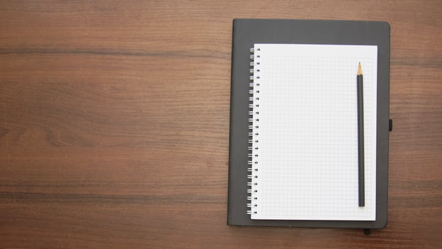 Notebook with pencil on wooden table top view photo