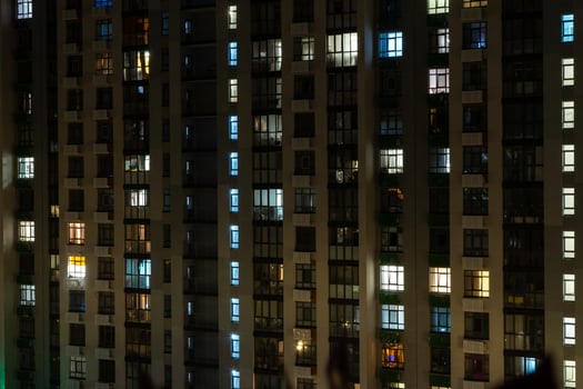 Night city. Multistorey residential building. The windows of the house glow in the dark. photo