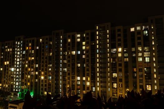 Night city. Multistorey residential building. The windows of the house glow in the dark. photo