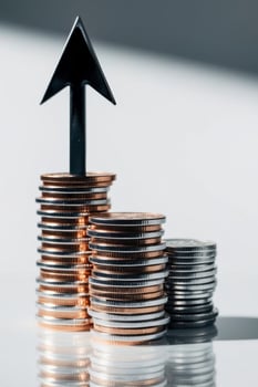 A stack of coins with an arrow pointing up photo