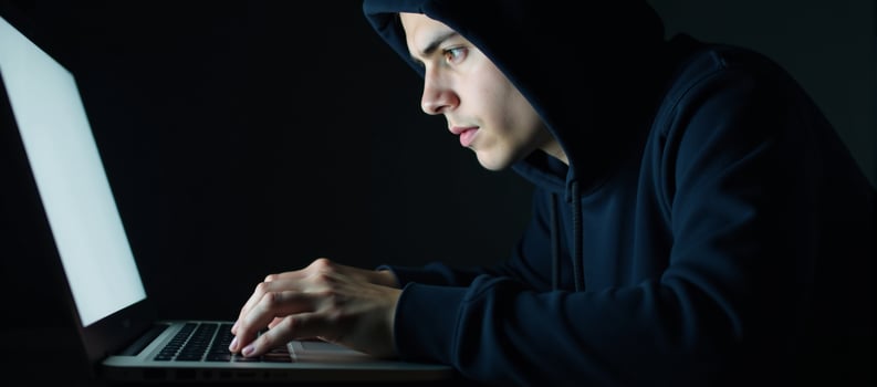 A hacker engages in cybercrime through his laptop on a dark backdrop while a young hacking prodigy battles him in an Internet Security Standoff photo
