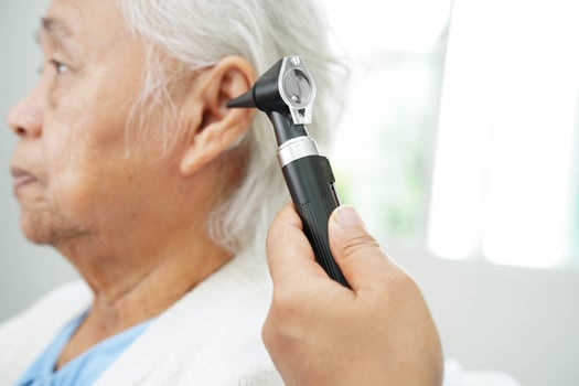 Otolaryngologist or ENT physician doctor examining senior patient ear with otoscope, hearing loss problem. photo