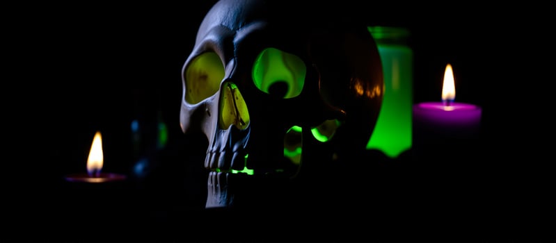 human skull with glowing green jar burning candles photo