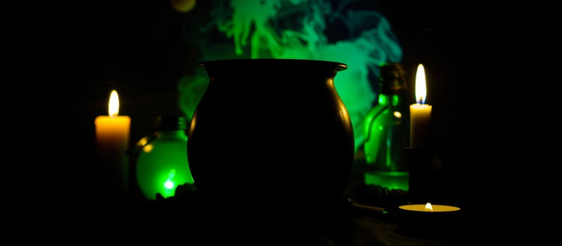 black cauldron surrounded by candles a green glass bottle photo