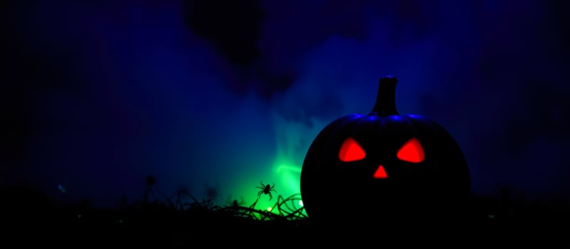 carved pumpkin with glowing red eyes sits a foggy field photo