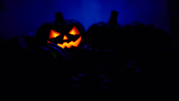 lighted jack-o-lantern stands out among a group pumpkins a blue glow photo