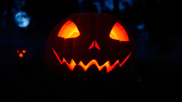 glowing jack-o-lantern stands against a dark night sky photo