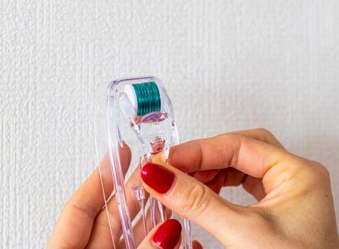 Woman holds micro needle skin care derma roller. Self care photo