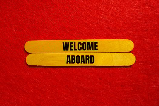 Welcome aboard message written on yellow wooden sticks with red background. Conceptual welcome aboard symbol. Copy space. photo