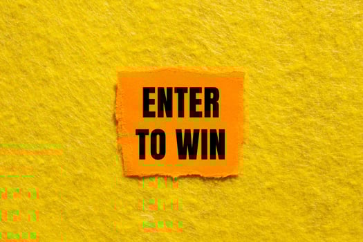 Enter to win message written on ripped torn orange paper piece with yellow background. Conceptual enter to win symbol. Copy space. photo