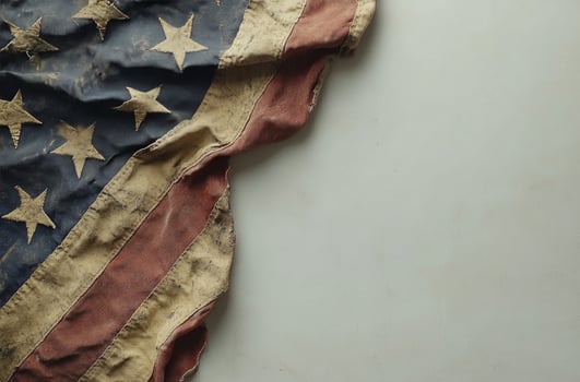 American flag draped subtly against a textured gray background in a minimalistic setting photo