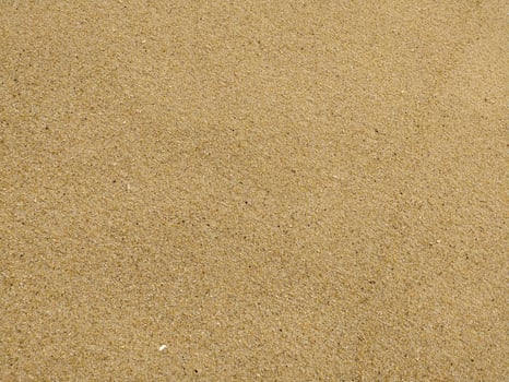 Fine golden sand covering a beach during a sunny day with clear skies, creating a serene and tranquil atmosphere for relaxation photo