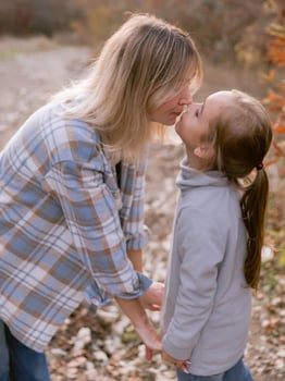Young mother kissing her beautiful little daughter outdoor with sunshine. photo
