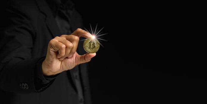 Businessman holding a bitcoin coin while standing over a black background photo