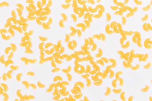 Scattered Uncooked Chifferi Rigati Pasta on White Background. Fat and Unhealthy Food. Classic Dry Macaroni Texture. Italian Culture and Cuisine. Raw Pasta photo