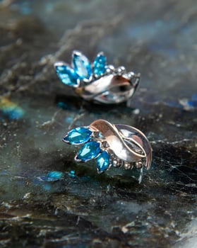 Silver earrings with blue topaz sparkling on dark background photo