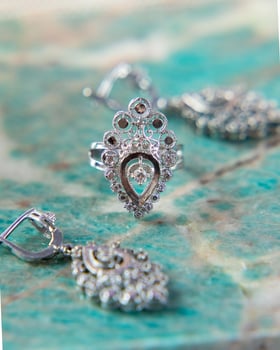 Silver ring with matching earrings on turquoise surface photo
