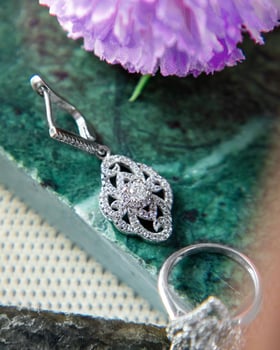 Silver earrings and ring with diamonds lying on green malachite stone photo