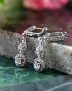 Silver earrings sparkling on green marble surface photo