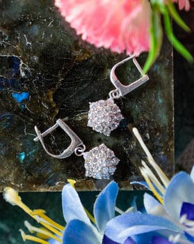 Pair of sparkling silver earrings with diamonds resting on stone surface photo
