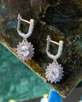Pair of sparkling silver earrings with diamonds resting on green malachite stone photo