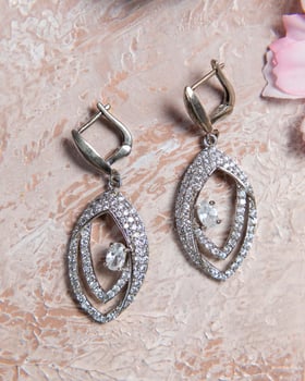 Pair of silver earrings with sparkling diamonds on beige background photo