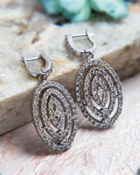 Pair of oval diamond earrings lying on stone surface photo