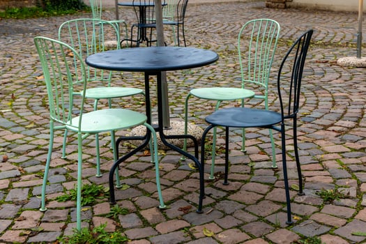 A black table with four chairs sits on a cobblestone patio photo