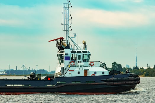 Black tug ship moving to the cargo terminal. Industrial service photo
