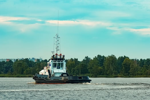 Black tug ship moving to the cargo terminal. Industrial service photo