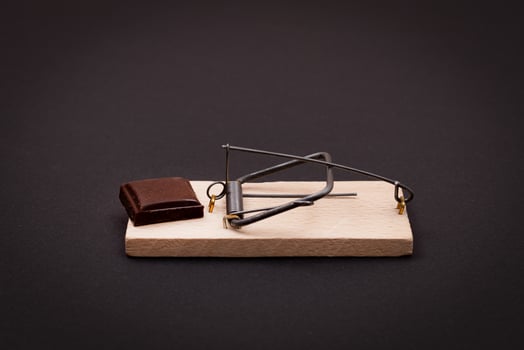 Temptation by Sweets or Chocolate Addiction - Sweet Wedge of Milk Chocolate in Wooden Mousetrap on Black Background photo