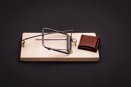 Temptation by Sweets or Chocolate Addiction - Sweet Wedge of Milk Chocolate in Wooden Mousetrap on Black Background photo
