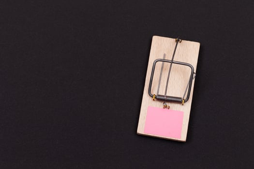 Blank Pink Sheet of Paper in Wooden Mousetrap - Template. Small Memo Paper in Mouse Trap on Black Background photo