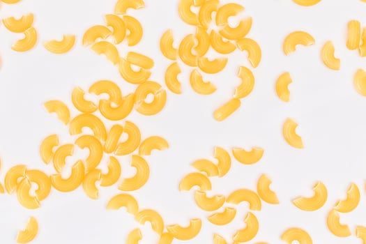 Scattered Uncooked Chifferi Rigati Pasta on White Background. Fat and Unhealthy Food. Classic Dry Macaroni Texture. Italian Culture and Cuisine. Raw Pasta photo