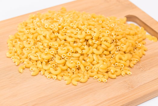 A Heap of Uncooked Chifferi Rigati Pasta on Wooden Kitchen Board. Fat and Unhealthy Food. Classic Dry Macaroni. Italian Culture and Cuisine. Raw Pasta photo
