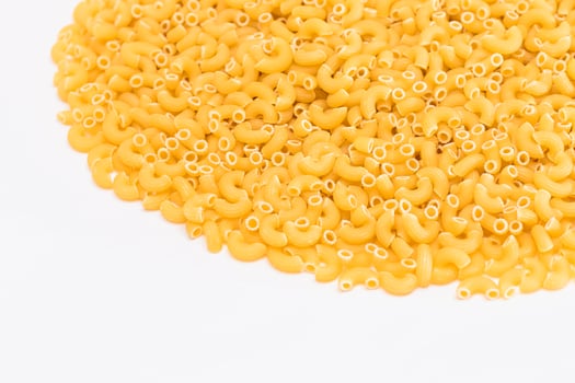 A Heap of Uncooked Chifferi Rigati Pasta on White Background. Fat and Unhealthy Food. Classic Dry Macaroni Texture. Italian Culture and Cuisine. Raw Pasta photo