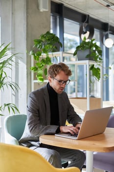 Focused businessman using laptop and working remotely in modern office cafeteria photo