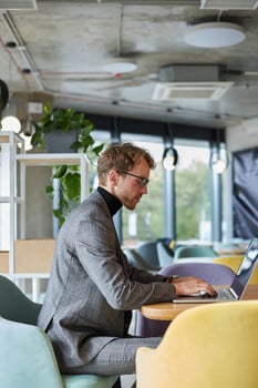 Focused businessman working on laptop in modern office cafeteria photo