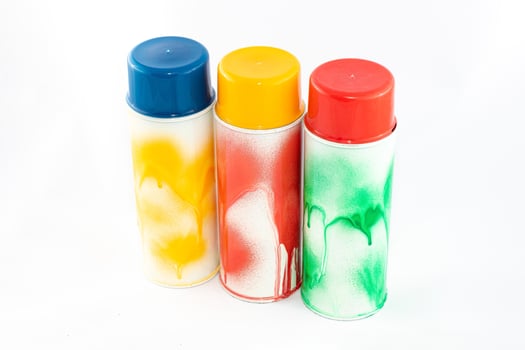 Three Colored Spray Paint Cans on White Background. Graffiti's Inventory - Close-Up Shot photo