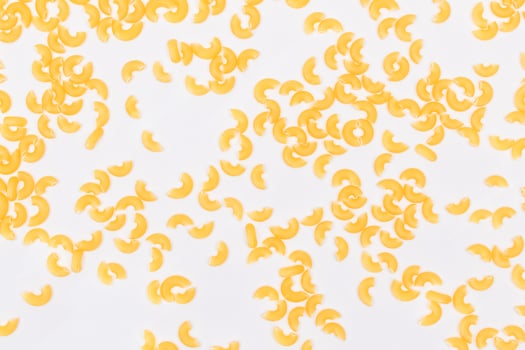 Scattered Uncooked Chifferi Rigati Pasta on White Background. Fat and Unhealthy Food. Classic Dry Macaroni Texture. Italian Culture and Cuisine. Raw Pasta photo