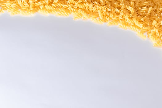 Uncooked Fusilli Pasta with Copy Space on White Background. Raw and Dry Macaroni. Fat and Unhealthy Food - Flat Lay photo