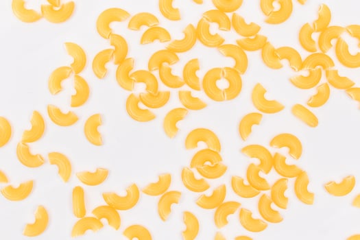 Scattered Uncooked Chifferi Rigati Pasta on White Background. Fat and Unhealthy Food. Classic Dry Macaroni Texture. Italian Culture and Cuisine. Raw Pasta photo