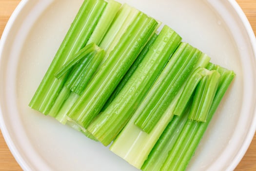 Fresh Chopped Celery Sticks with Water Drops in White Bowl - Top View. Vegan and Vegetarian Culture. Raw Food. Healthy Diet with Negative Calorie Content photo