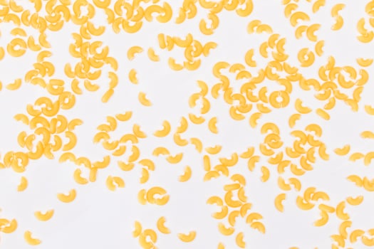 Scattered Uncooked Chifferi Rigati Pasta on White Background. Fat and Unhealthy Food. Classic Dry Macaroni Texture. Italian Culture and Cuisine. Raw Pasta photo