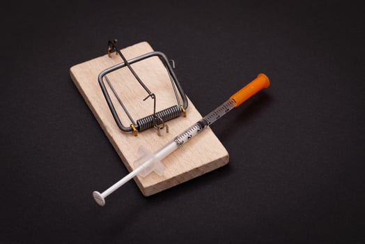 Drug Addict, Heroin Hazard or Dose Trap Concept - Disposable Insulin Syringe with Drug Dose Inside Lying in Wooden Mousetrap on Black Background photo