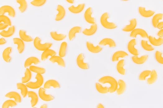 Scattered Uncooked Chifferi Rigati Pasta on White Background. Fat and Unhealthy Food. Classic Dry Macaroni Texture. Italian Culture and Cuisine. Raw Pasta photo