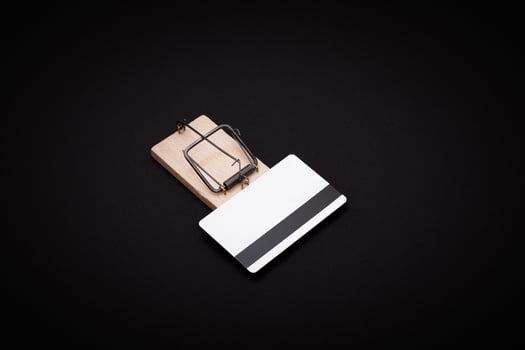 Credit Risk and Loan Trap - White Blank Credit Card Template in Wooden Mouse Trap on Black Background photo